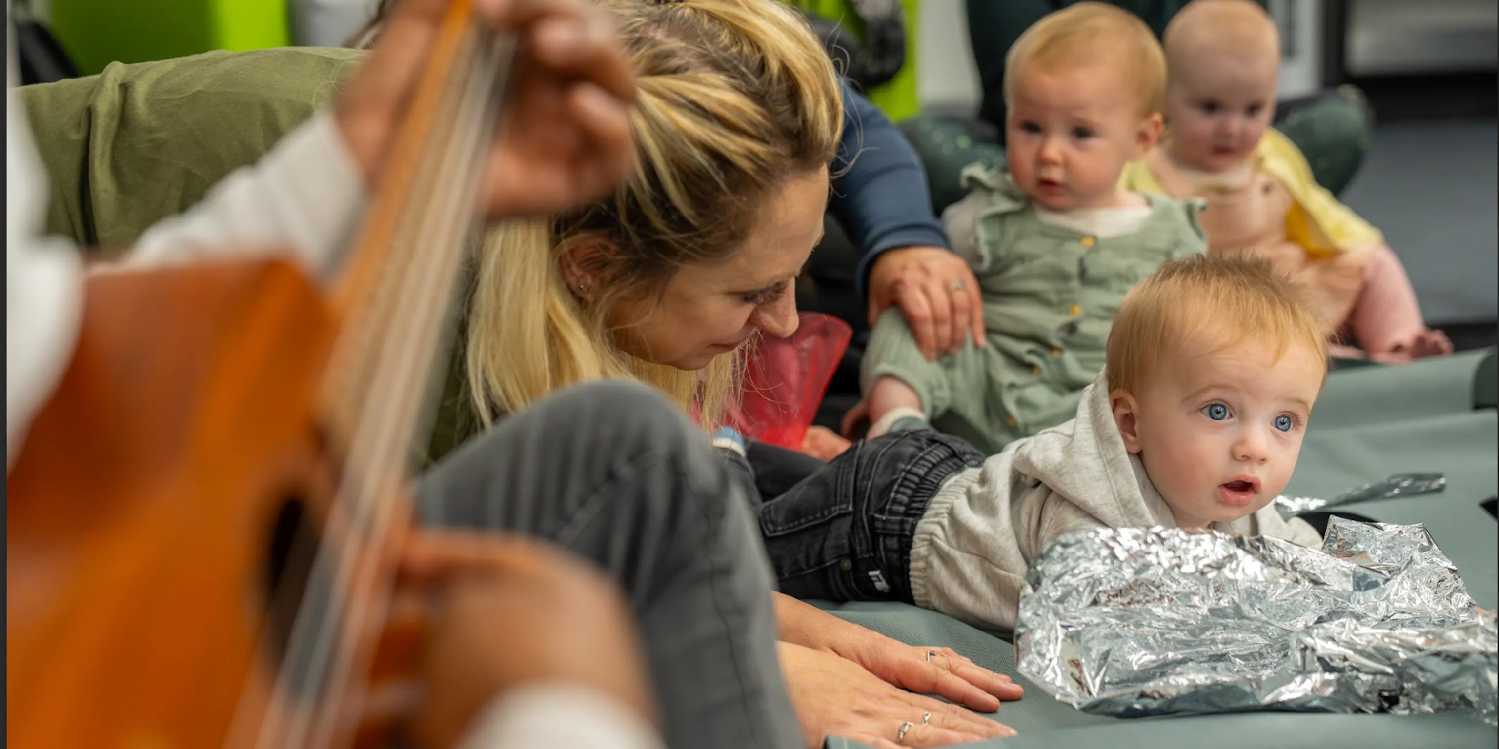 A group of children and parents/carers in a Playground session interacting with each other and the artists