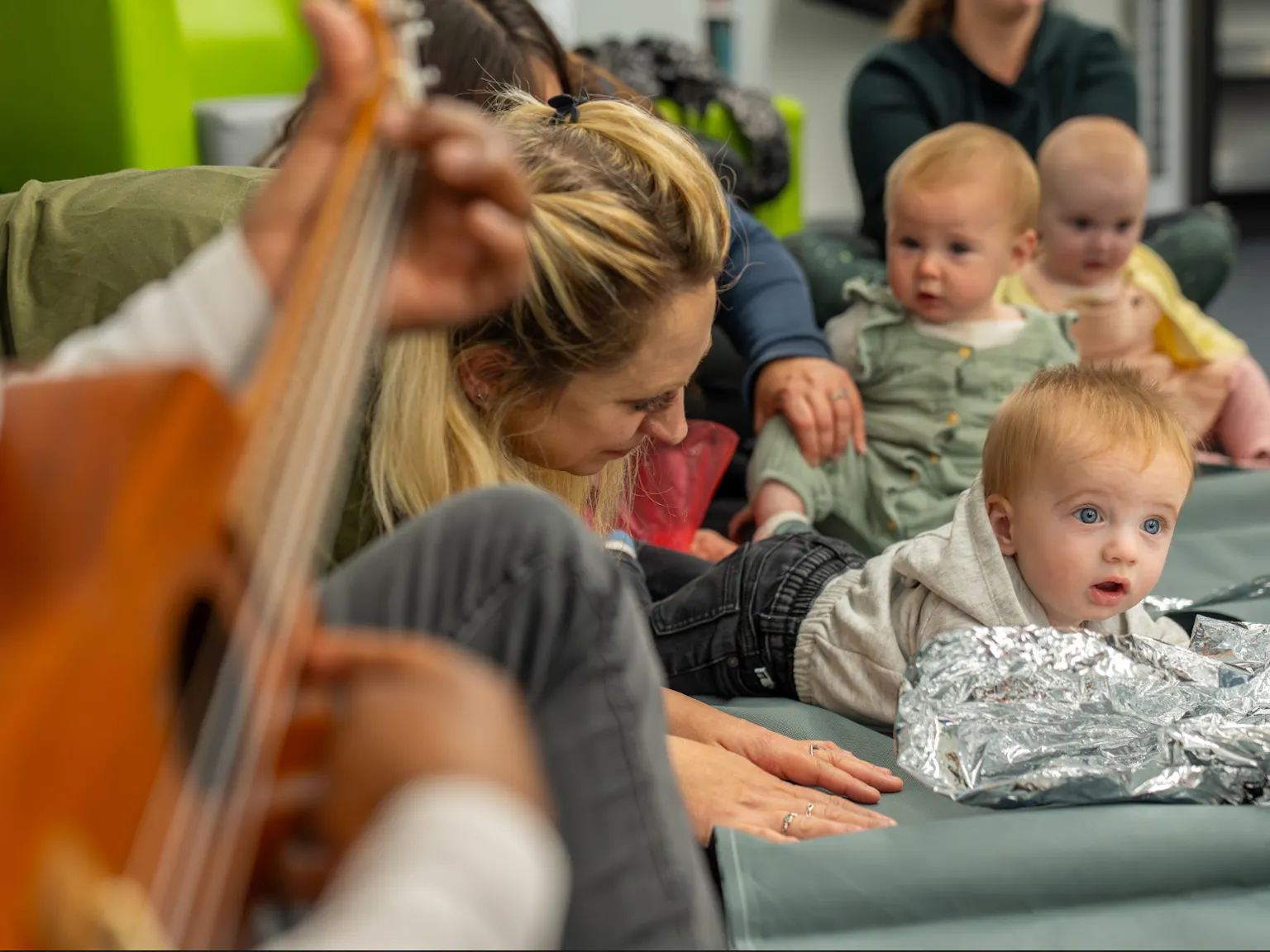 A group of children and parents/carers in a Playground session interacting with each other and the artists