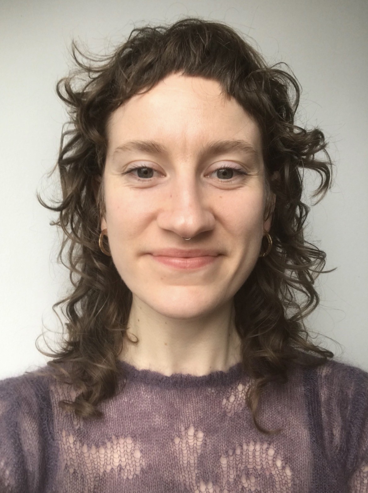 Profile image of woman with brown curly hair and a short fringe