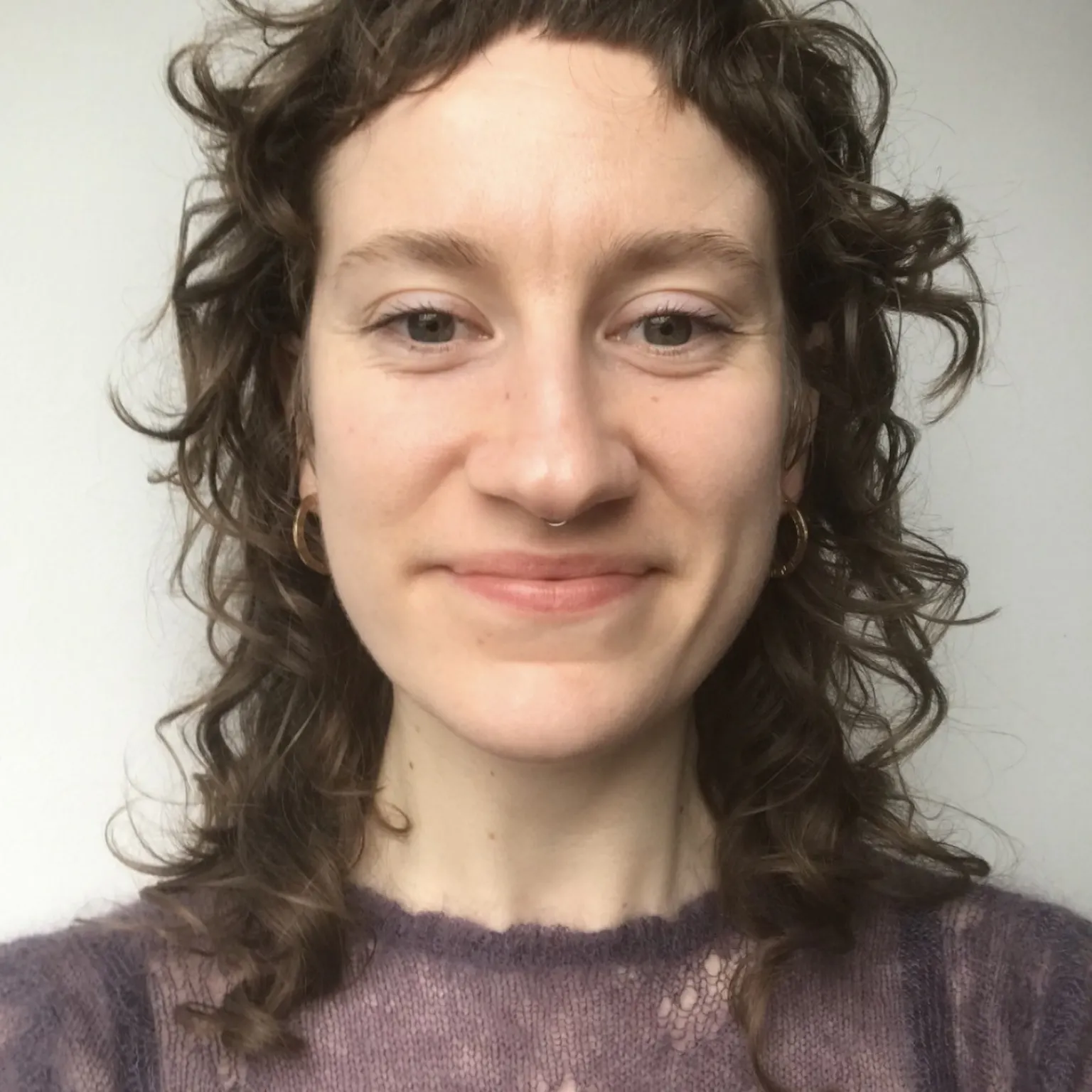 Profile image of woman with brown curly hair and a short fringe
