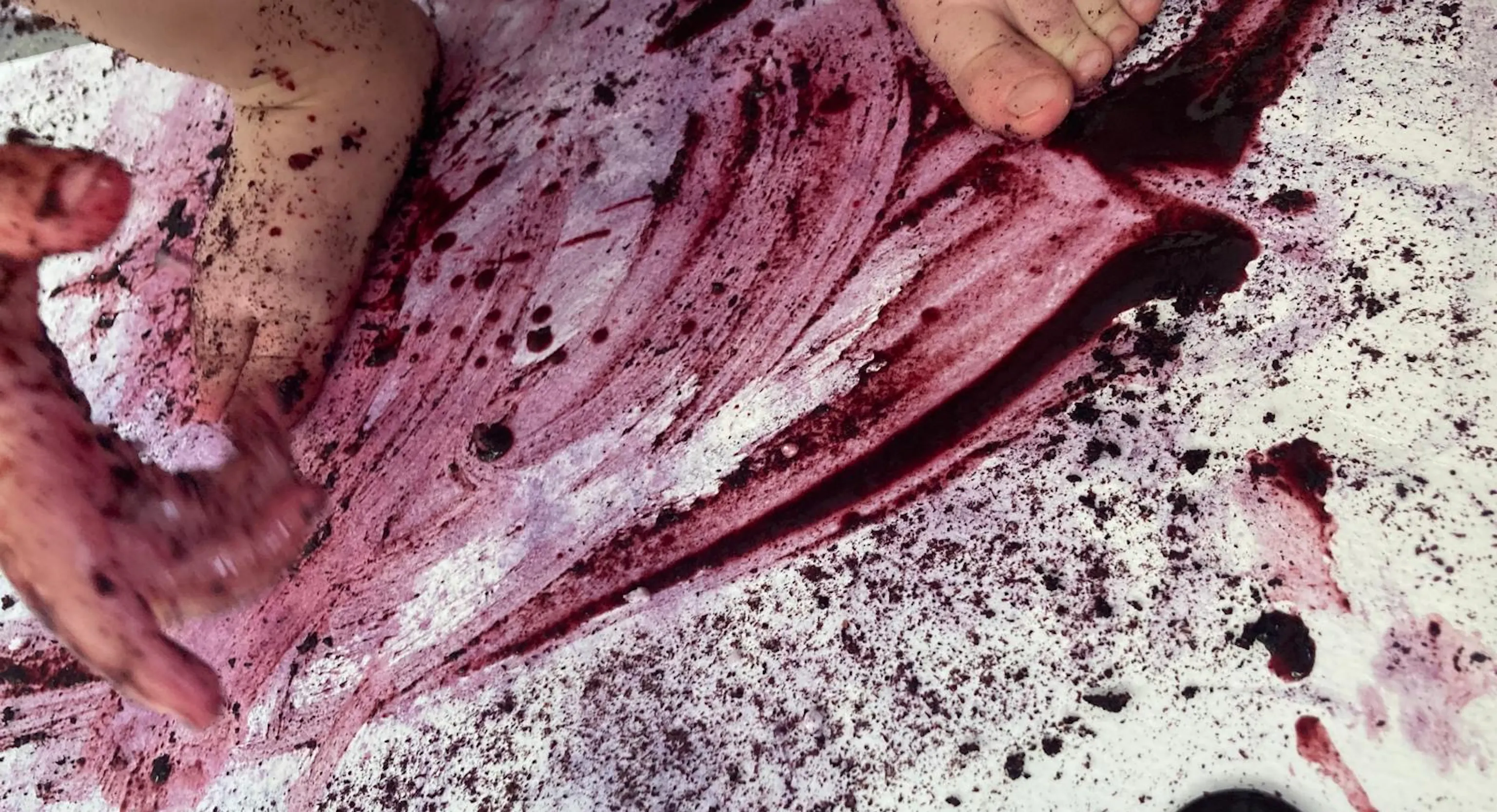 An abstract painting created by a young child's feet and hands. They have used blueberry juice and lemon to create the marks in the painting.