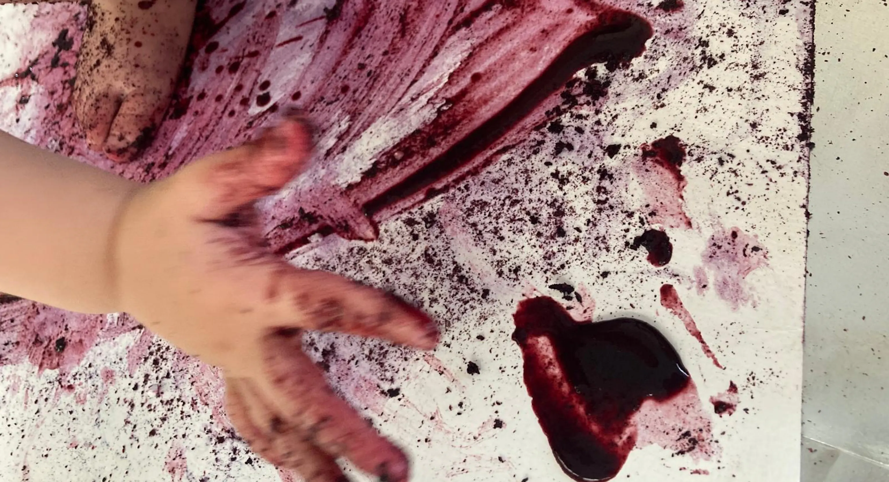 A baby's hand on a piece of paper with purple/red paint