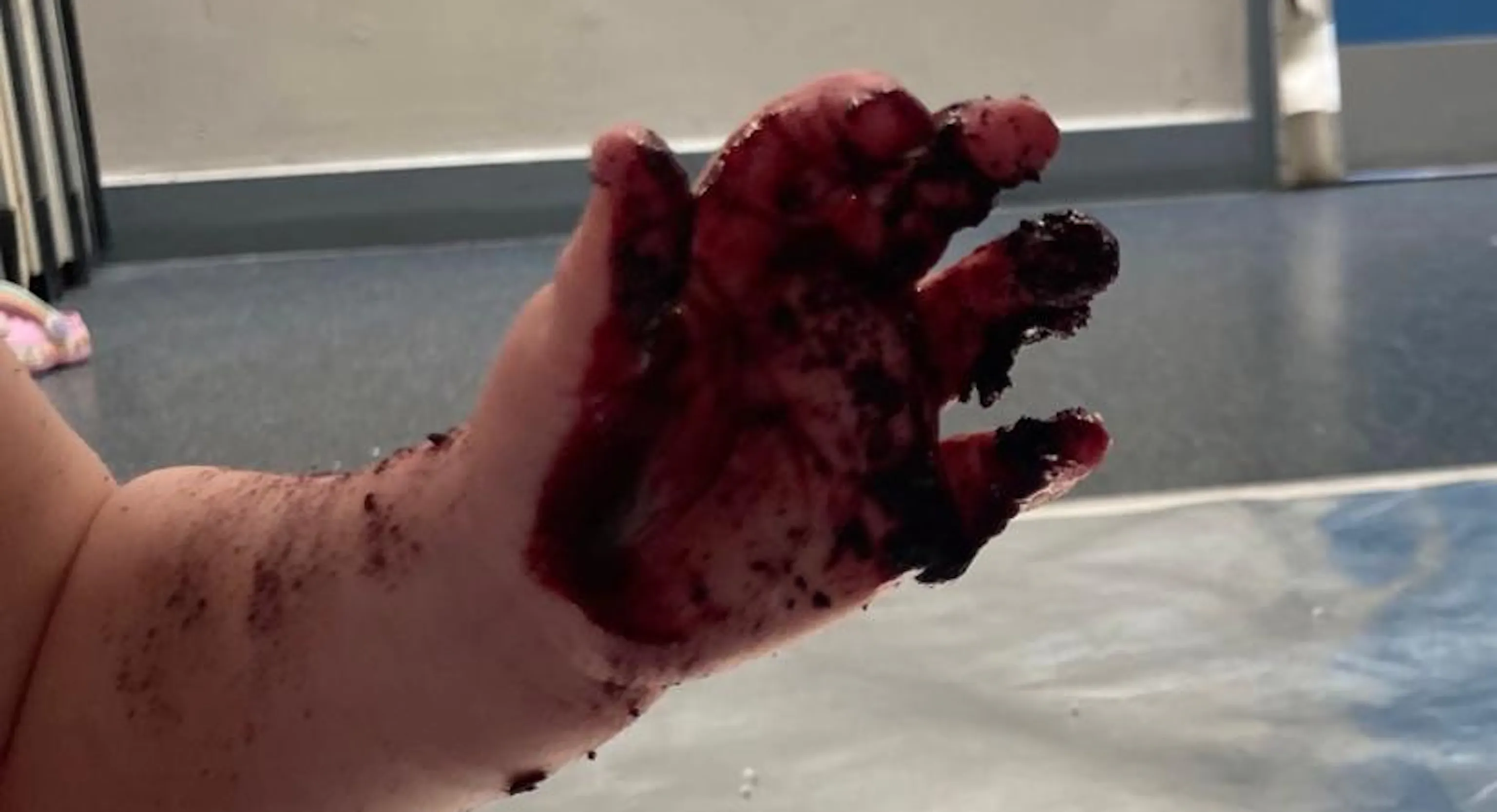 A close up of young child's hand covered in blueberry juice after they explore and engage with new materials.
