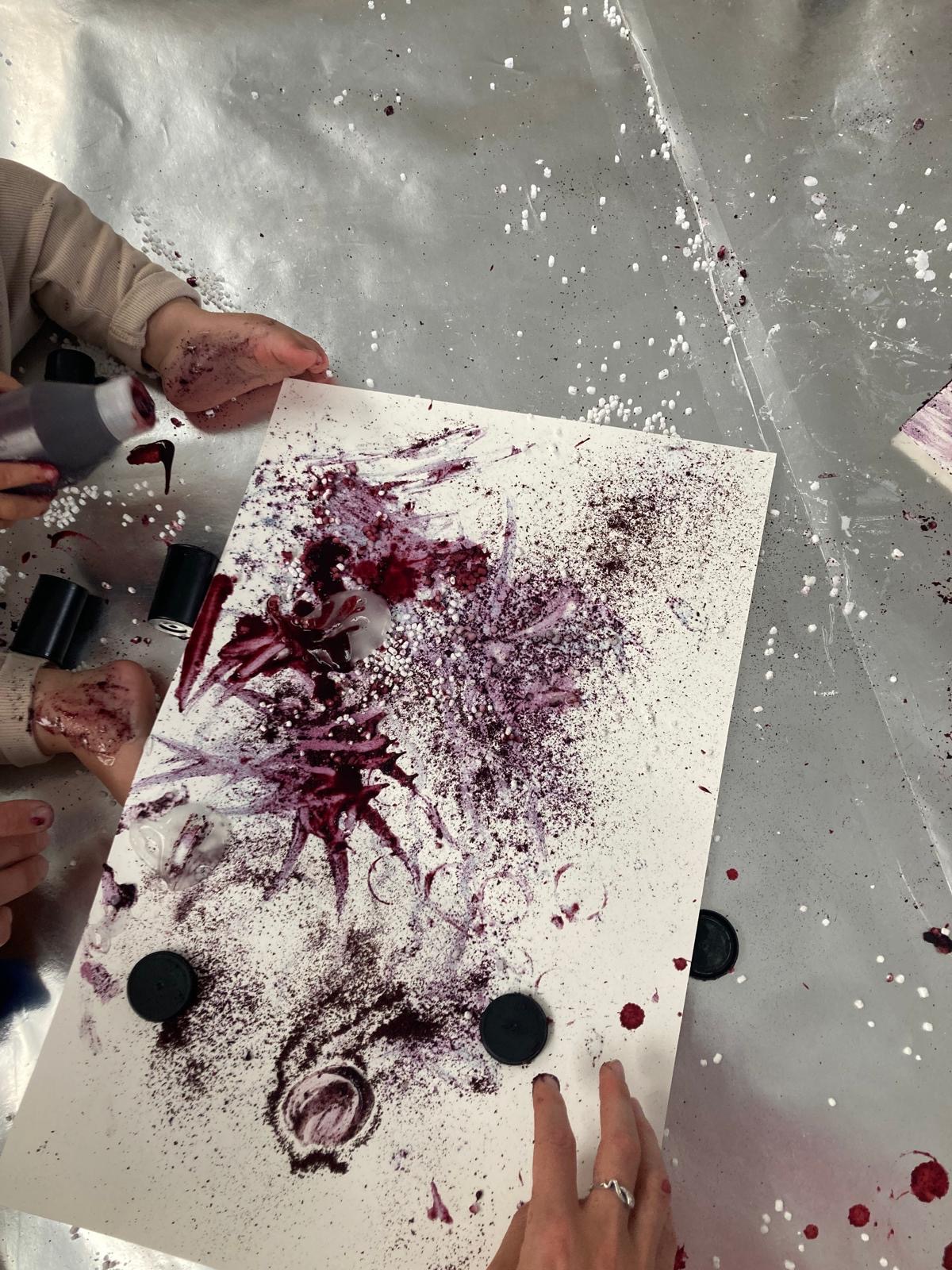  A young child paints an abstract image using blueberry juice and lemon.