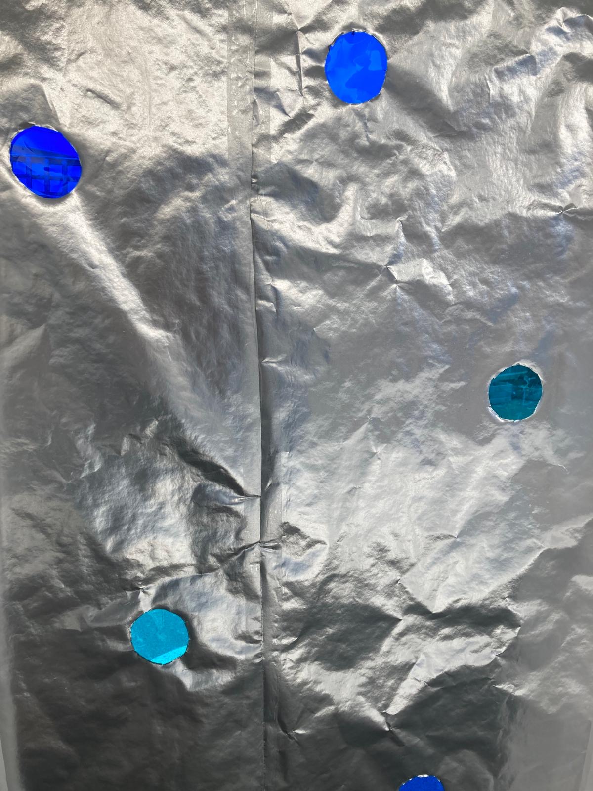 A close up of tinfoil with painted blue spots.