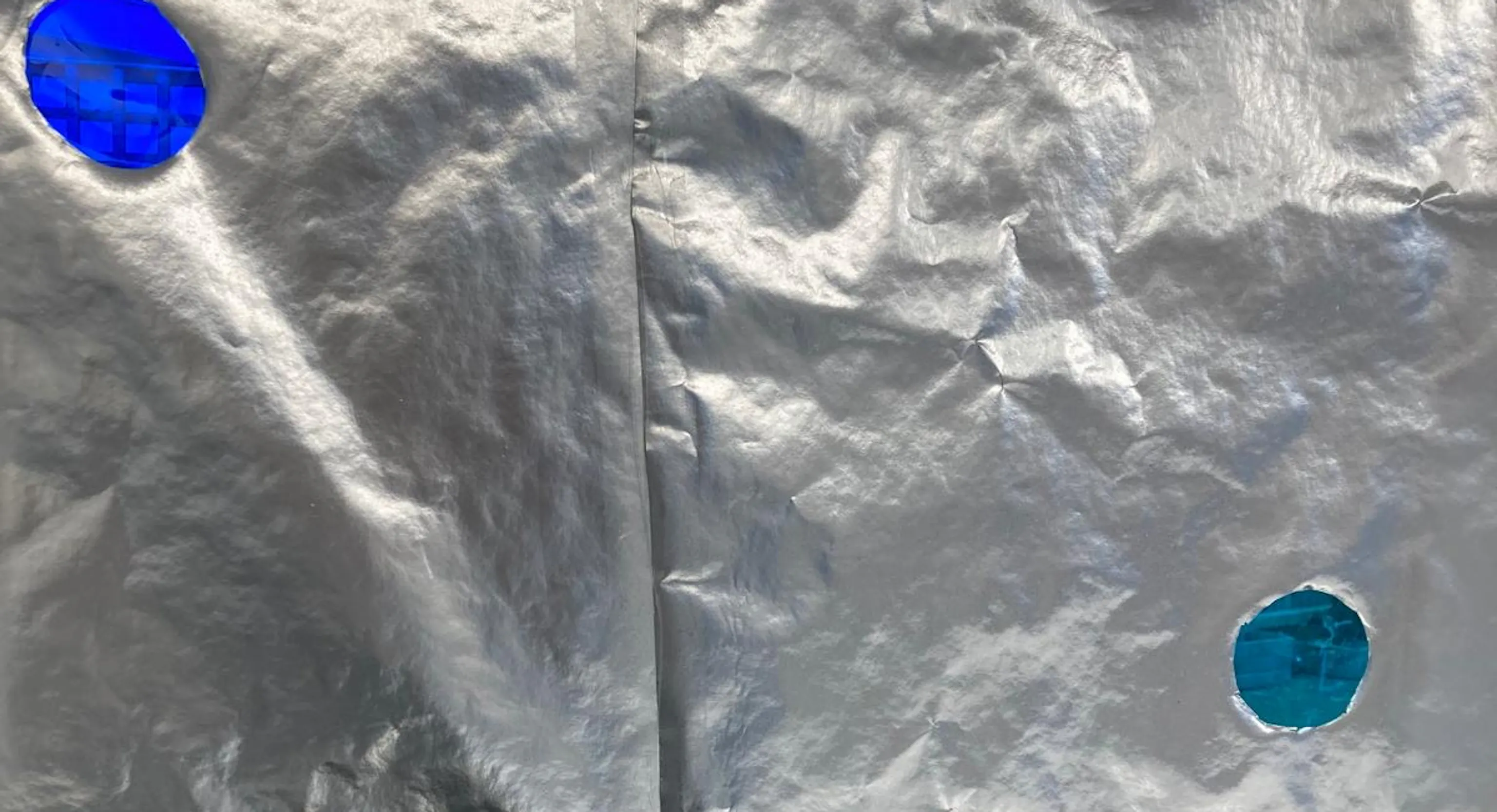 A close up of tinfoil with painted blue spots.