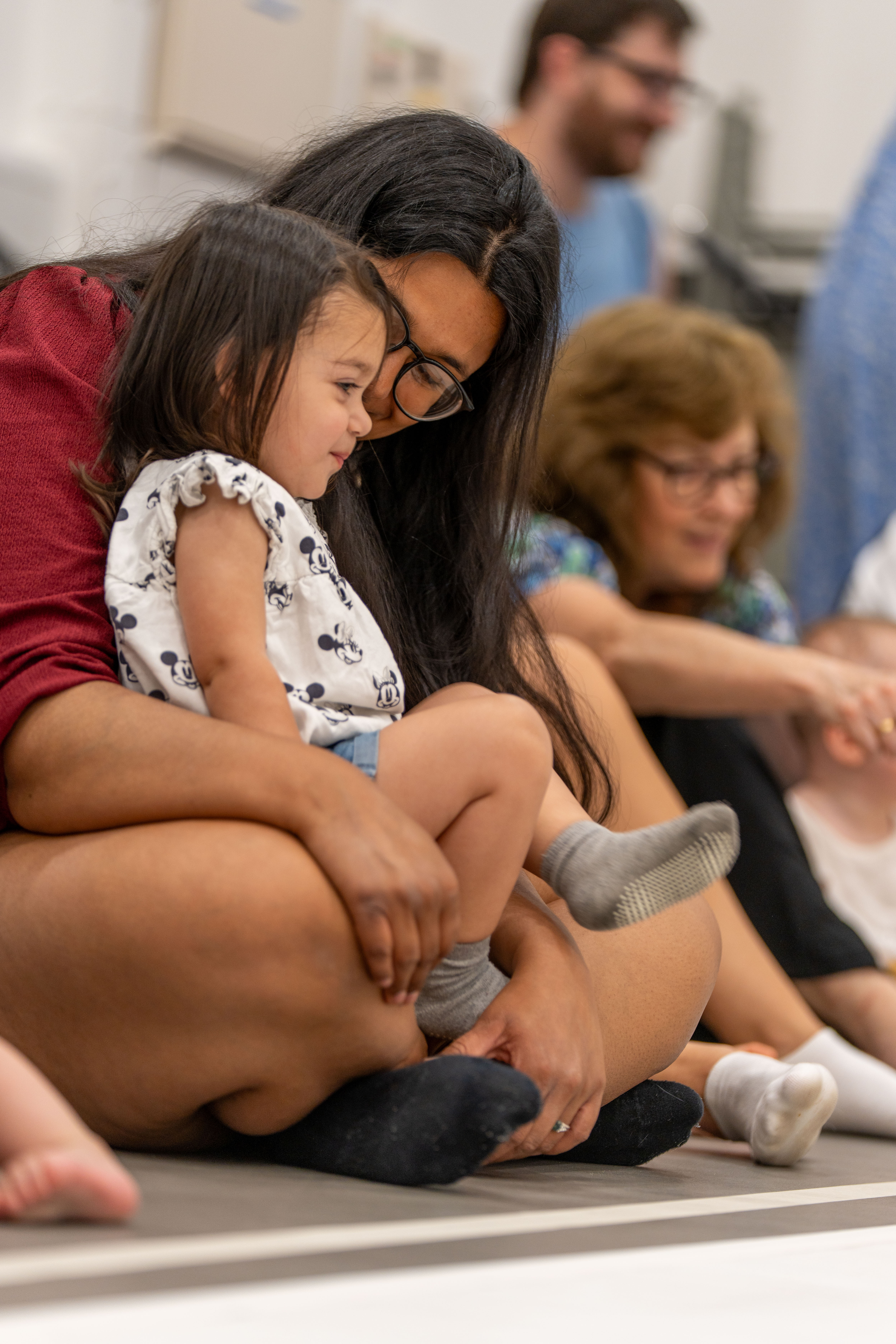 A young child sat on their parent/carer's lap and smiling 
