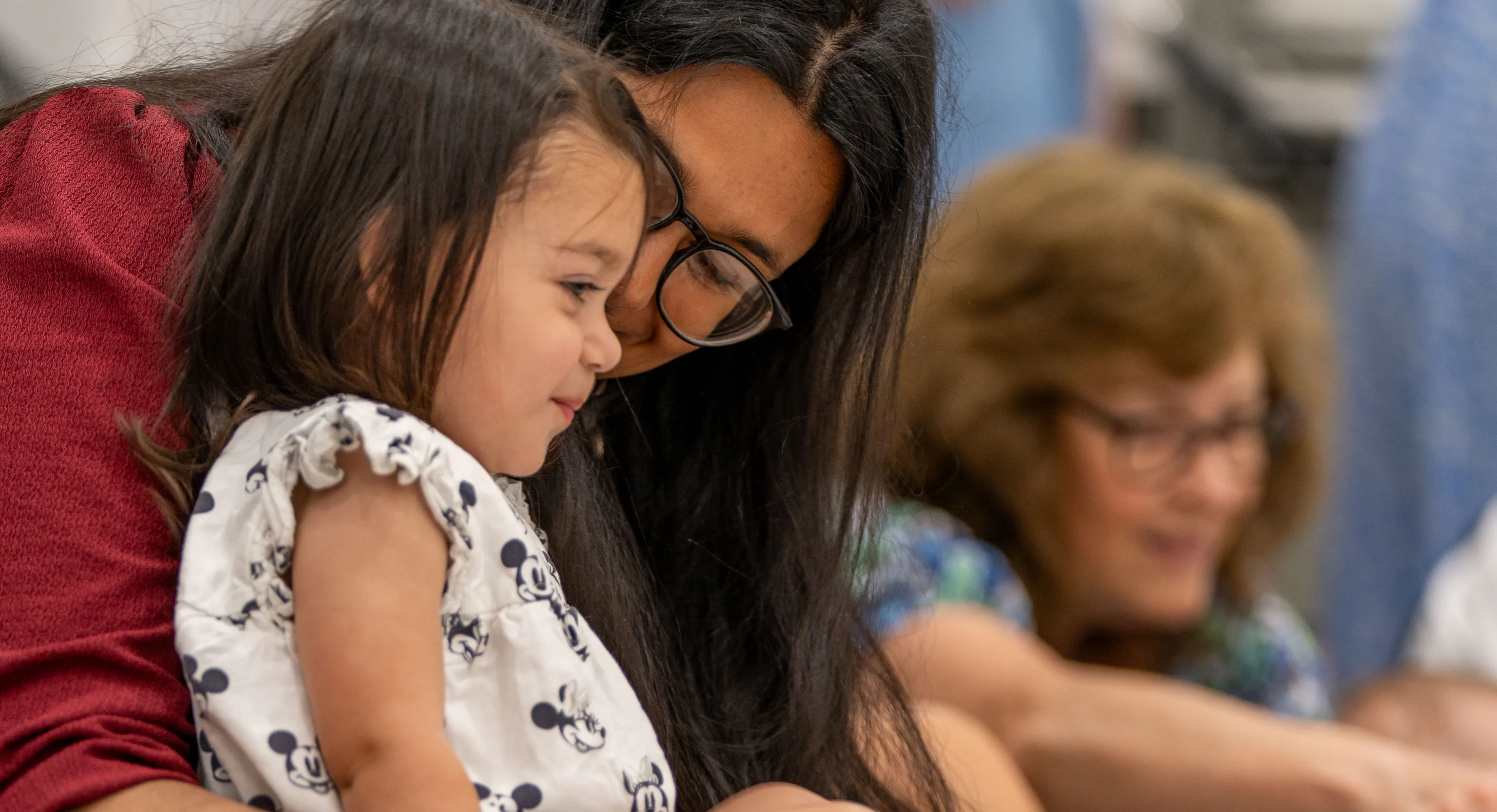A young child sat on their parent/carer's lap and smiling
