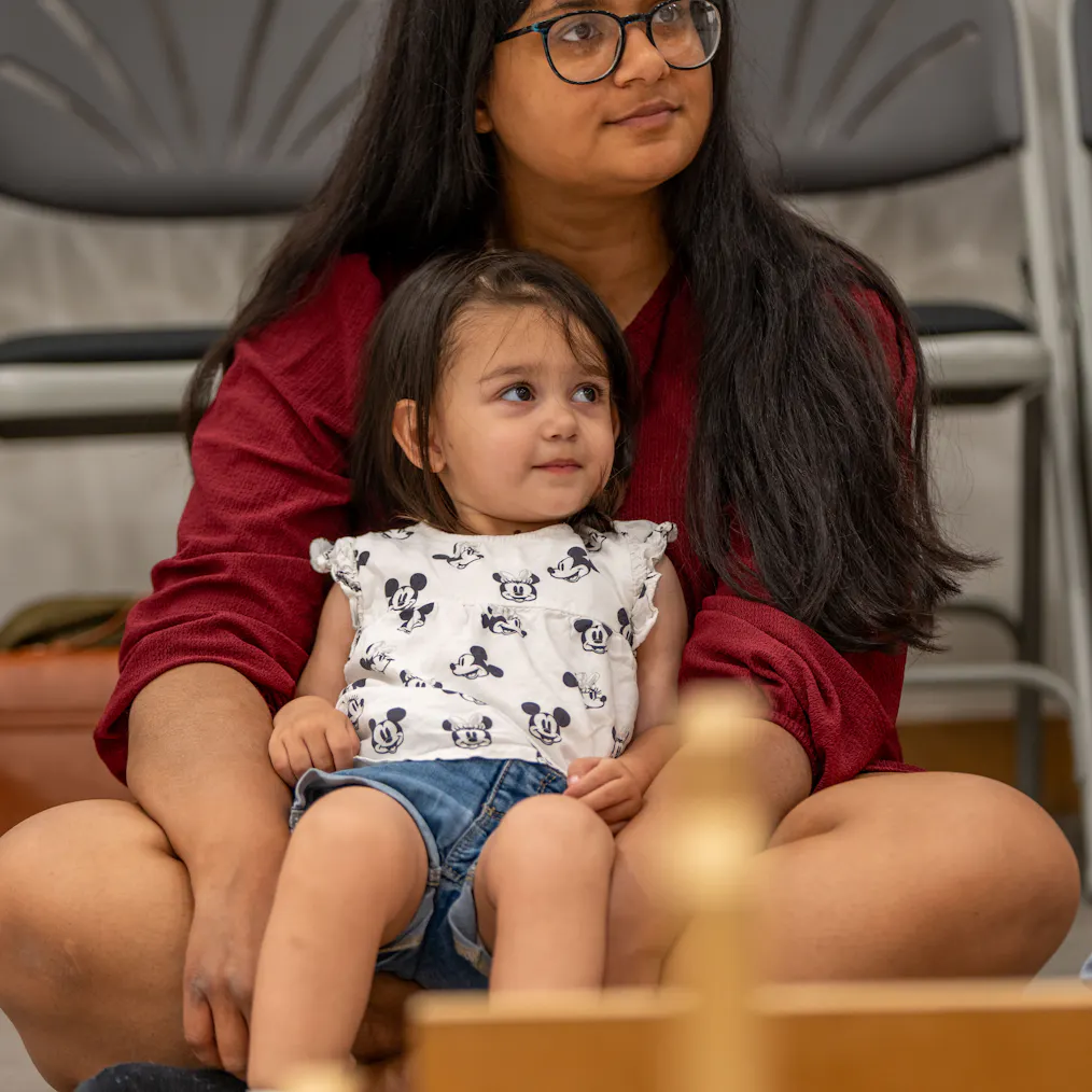 A young child sitting with their mother/carer