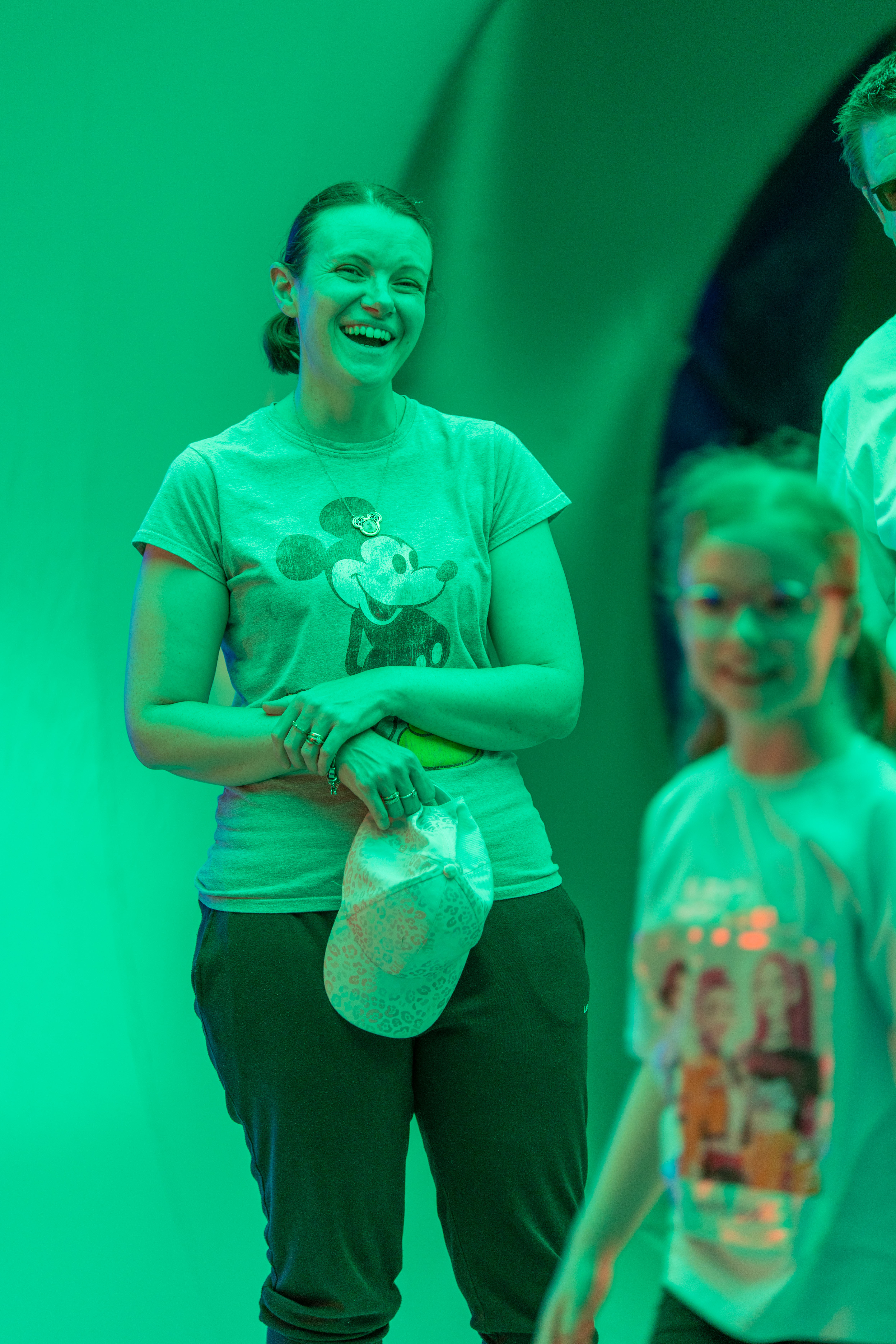 A parent/carer and child are smiling inside a green lit inflatable 