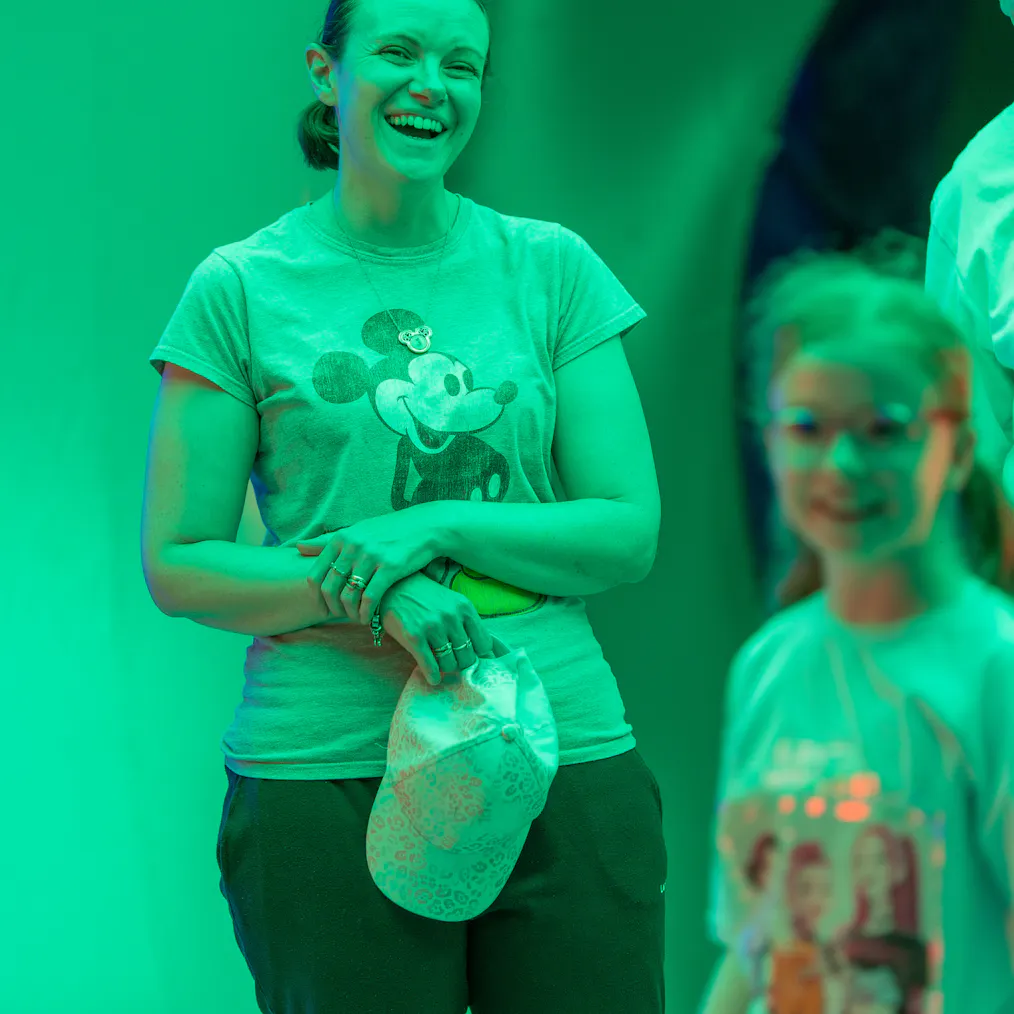 A parent/carer and child are smiling inside a green lit inflatable