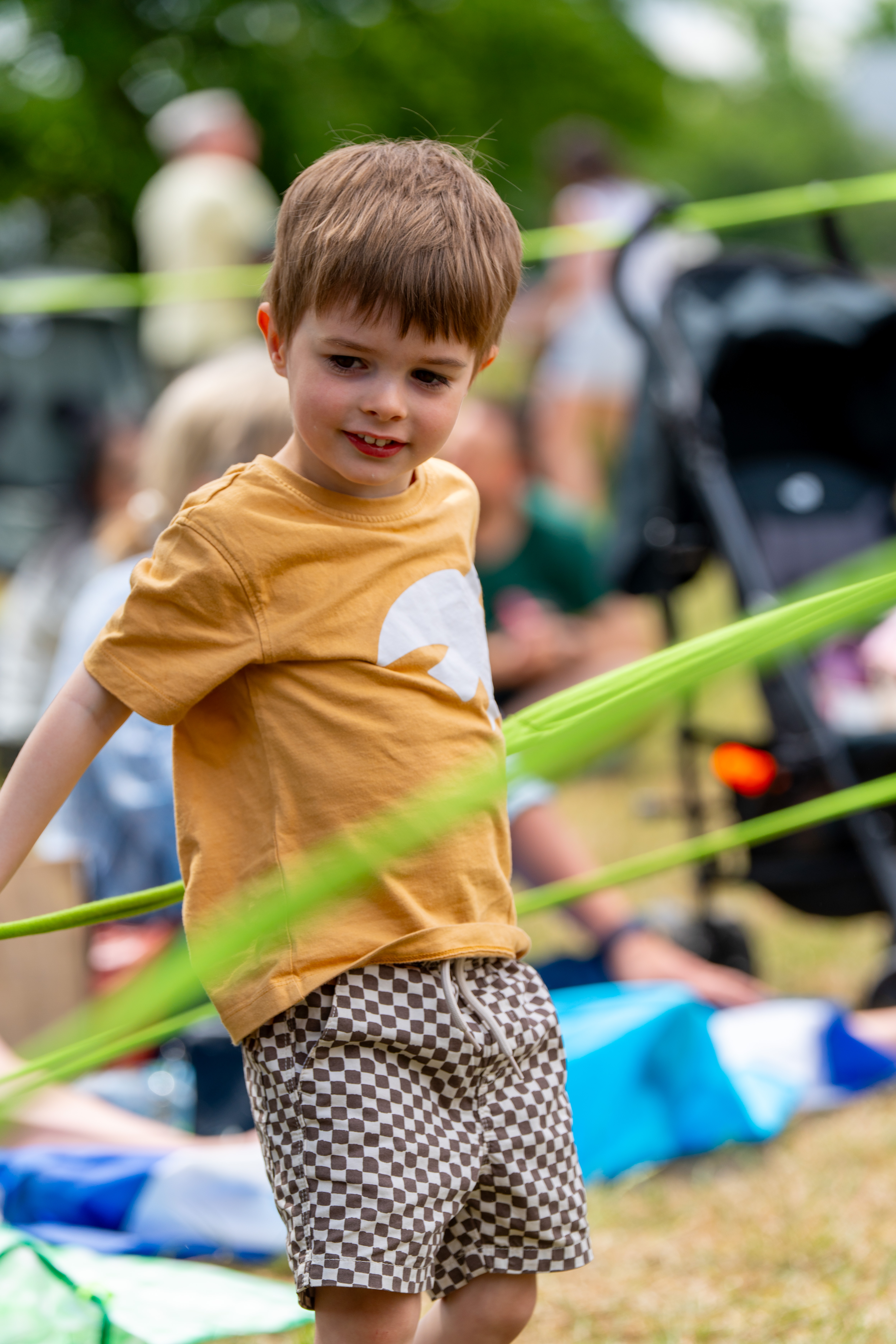 A child smiling with green rope around them as part of a performance 