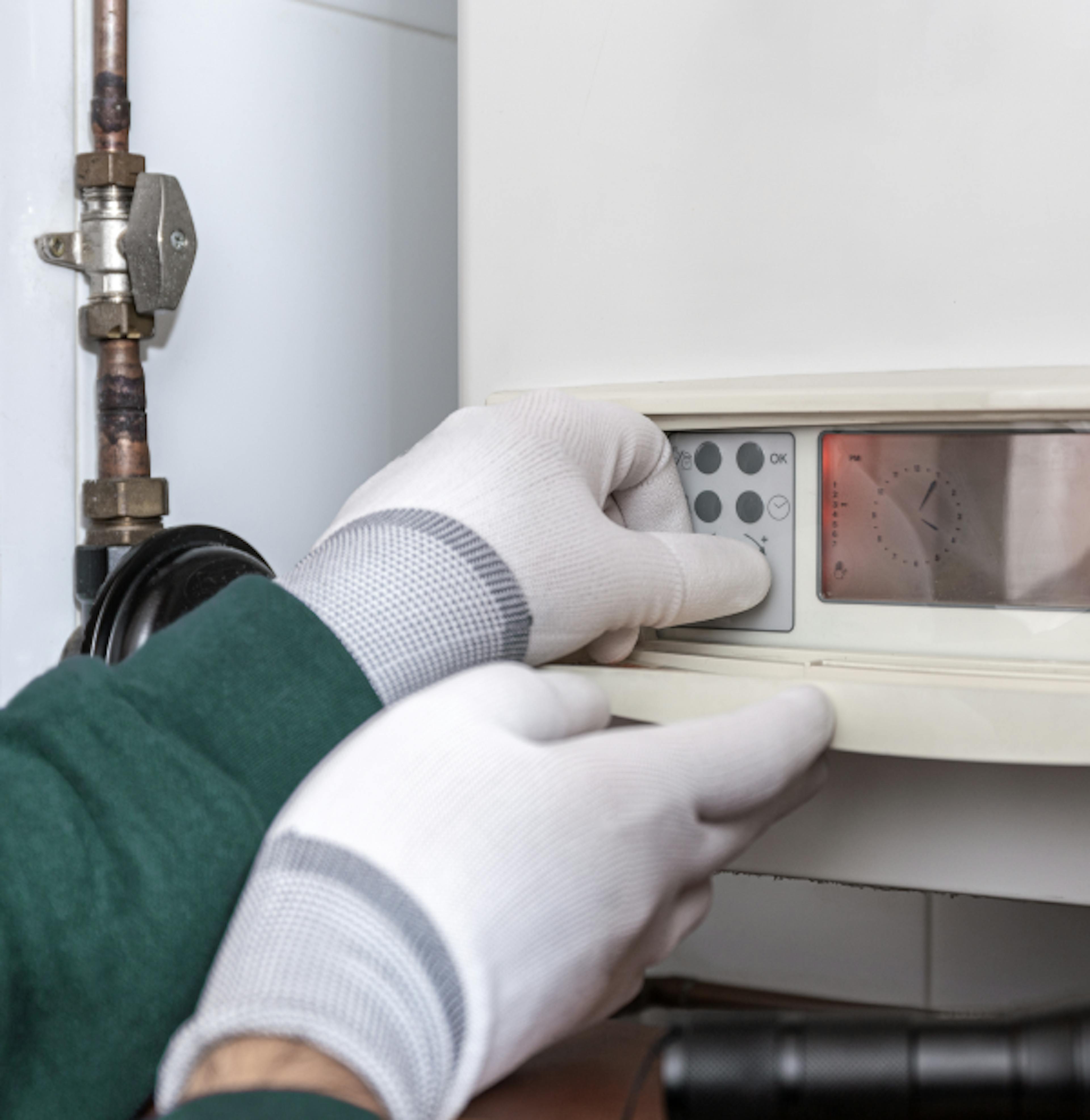 A plumber adjusts a boiler