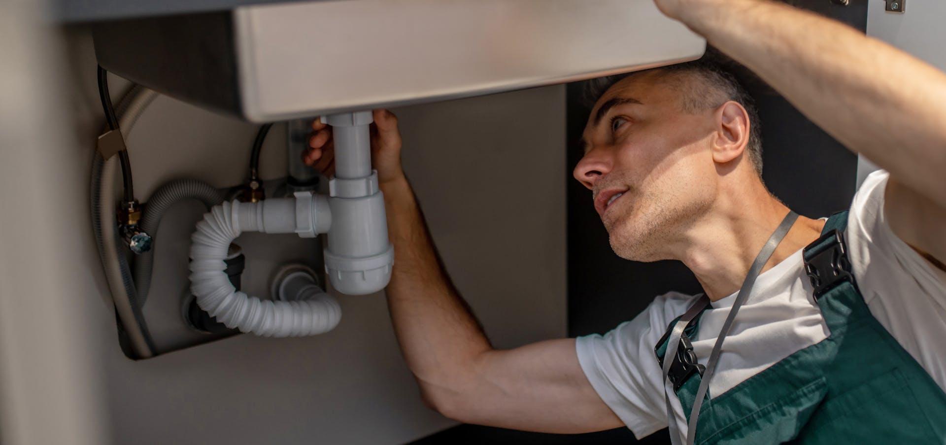 A plumber repairs a siphon