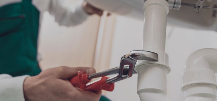 A plumber tightens a siphon