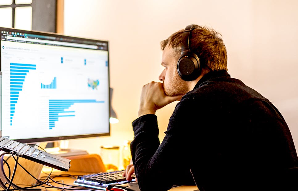 man at desk with headphones look at computer of dash enterprise