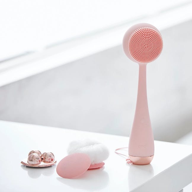 Blush PMD Clean Body on countertop with interchangeable attachments. 