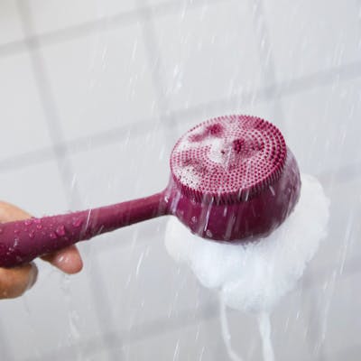 Woman holding PMD Clean Body in shower. 