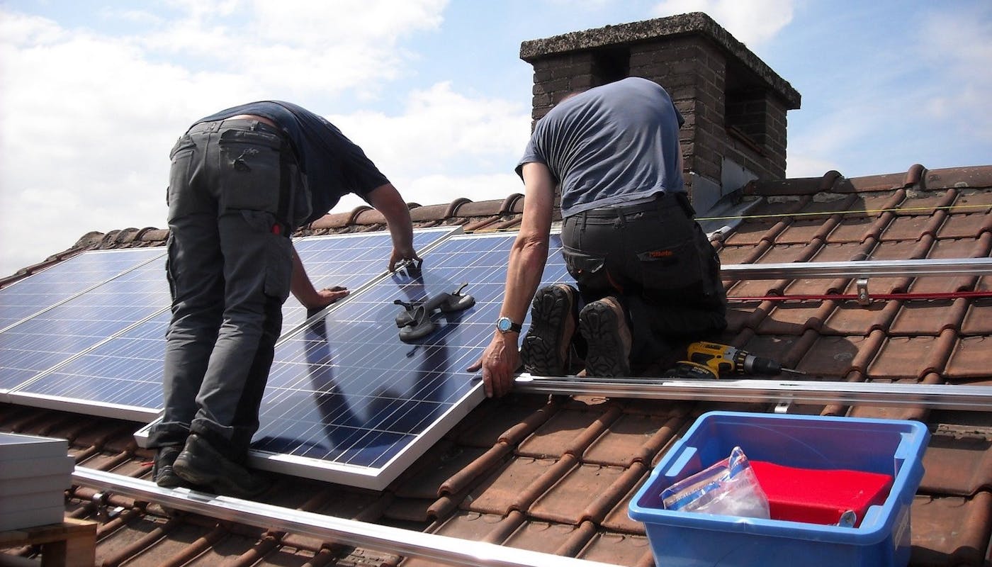 ouvriers qui installent des panneaux solaires sur un toit 