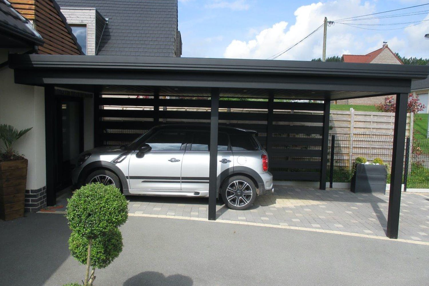 carport en pic noir avec une voiture en dessous