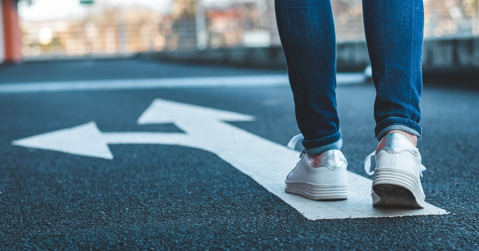 Woman walking on directional sign on asphalt road