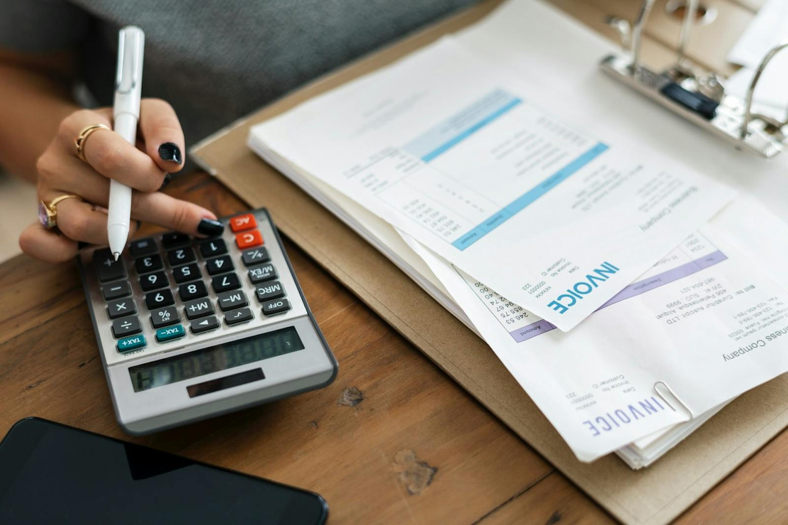 Close up of mobile developer using calculator and checking revenue stats