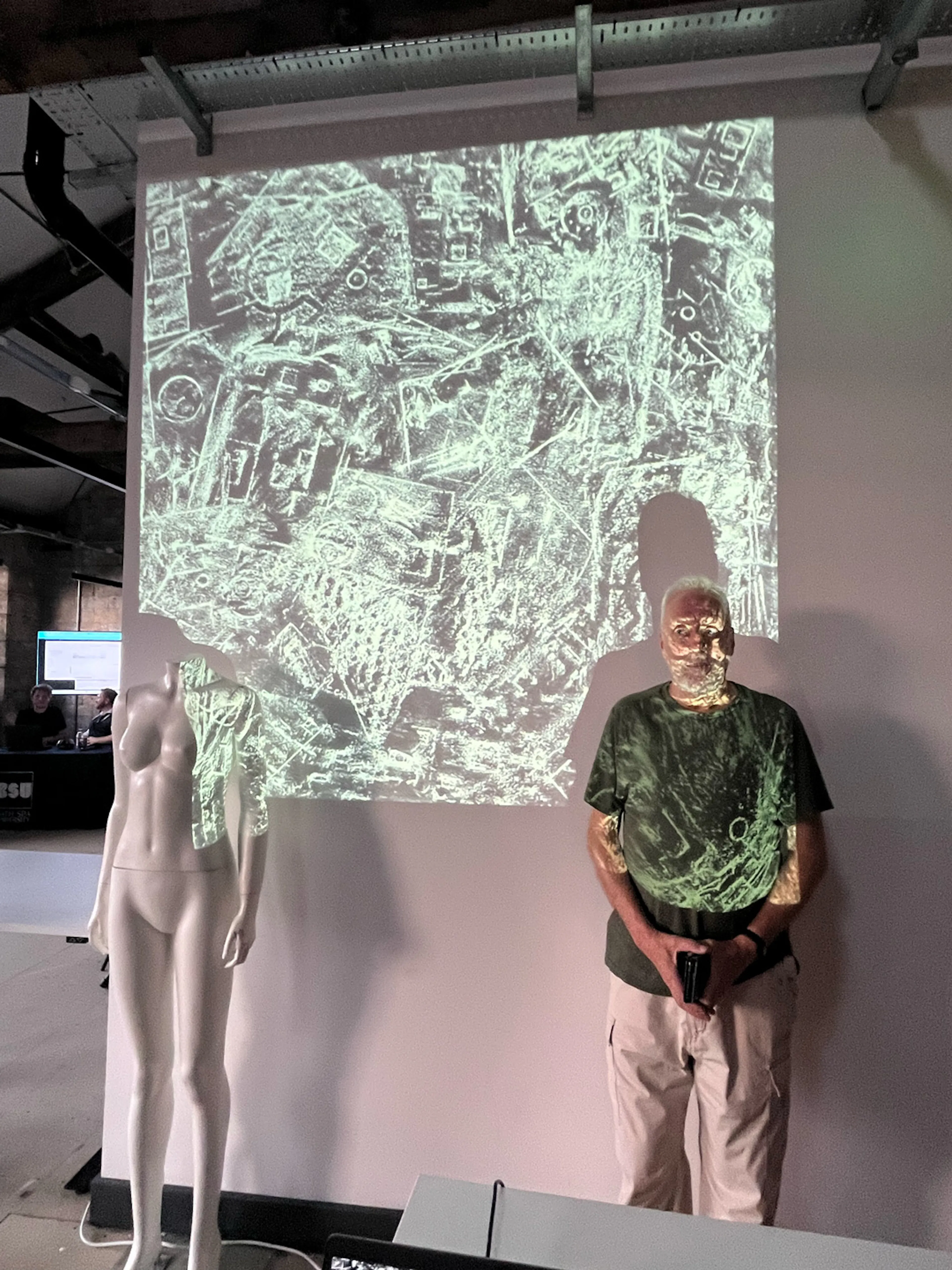 Artist Brian Gibson standing in front of his artwork projected on a wall. 