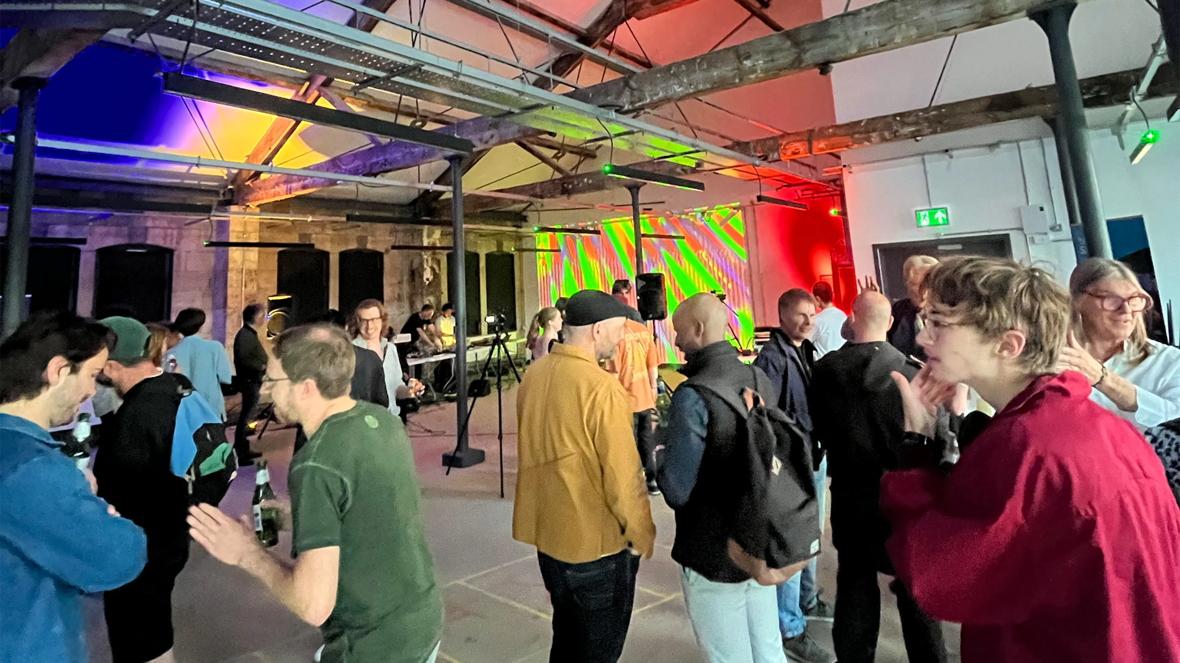 A wide shot of audience members enjoying the event. Projected visuals in the background. 