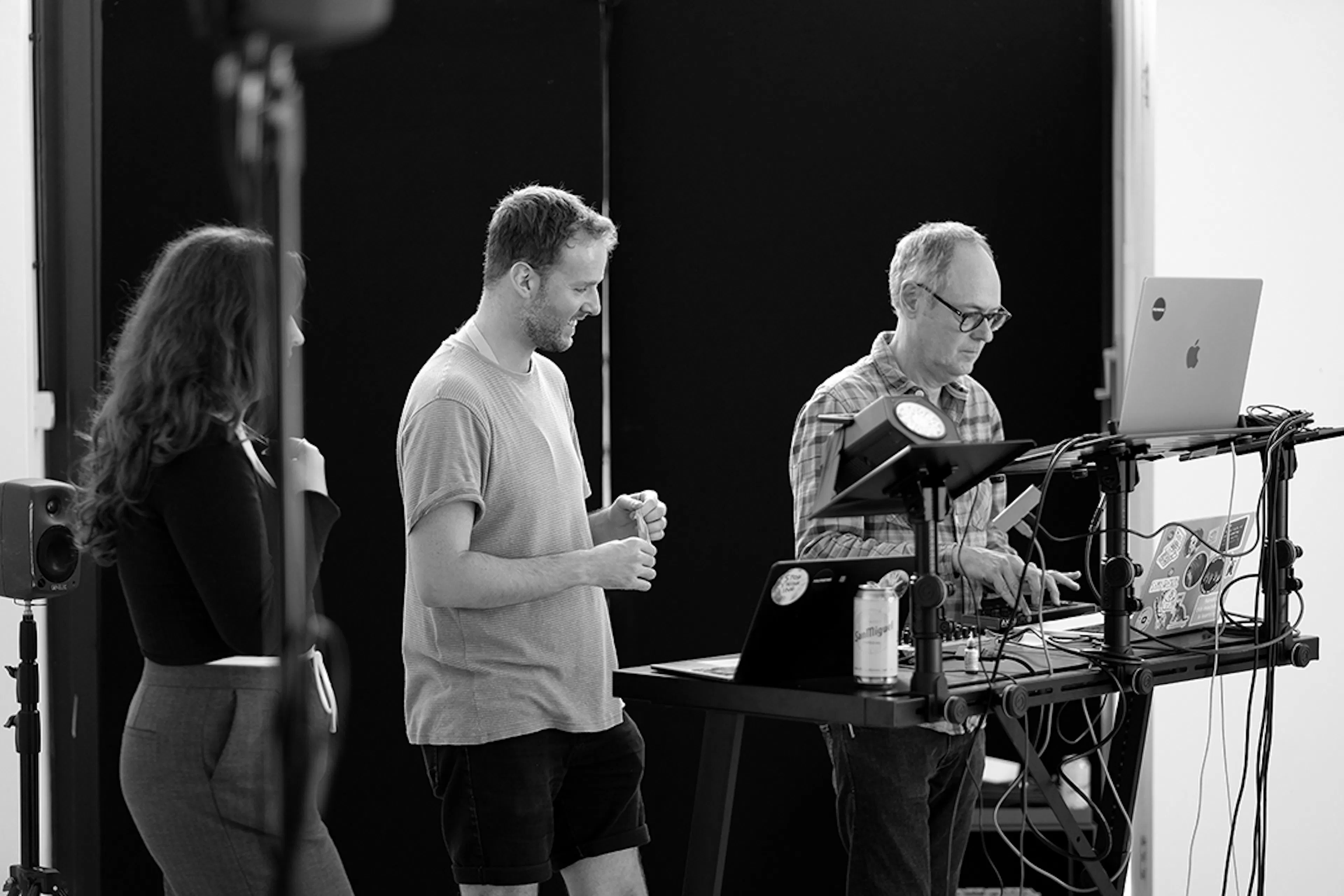 Charlotte Piper and Nigel Fryatt watching Dave Webb test his setup during the install for the event. Black and white. 
