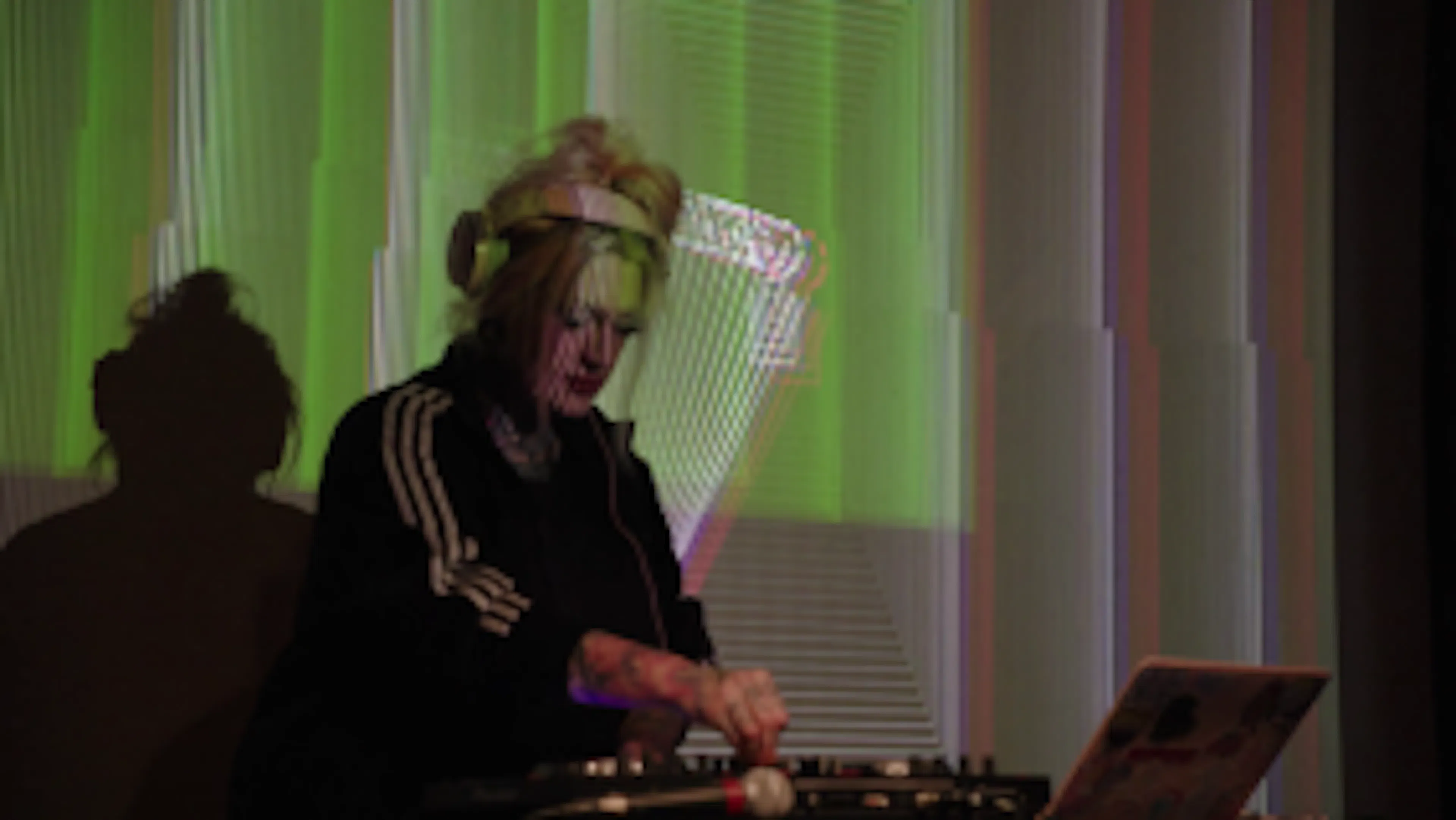 Close up of Remy Melee dj'ing in front of large projected visuals.
