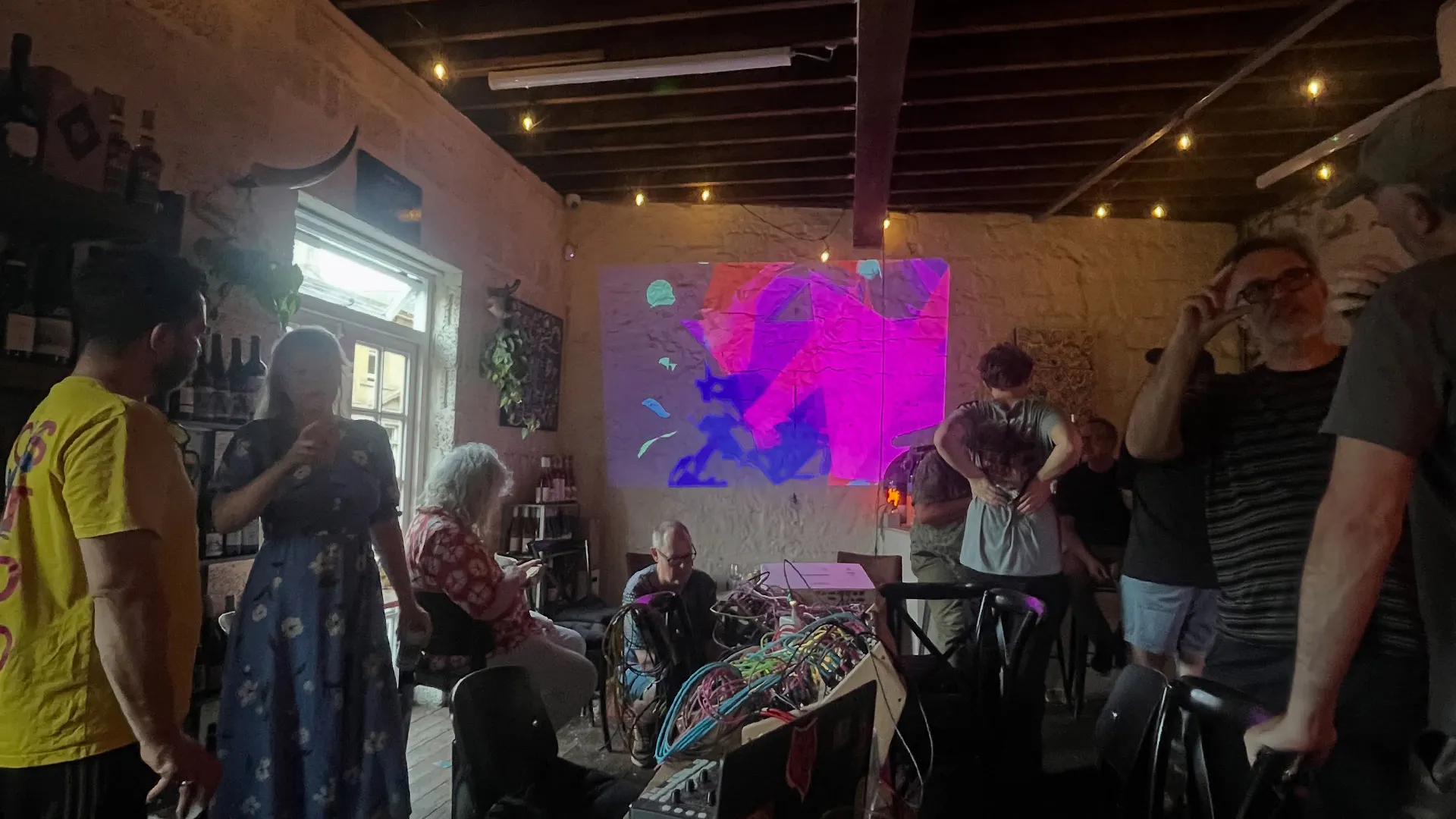 PVSH setup on tables inside Wolf Wine as audience members enjoy the event scattered around the room.
