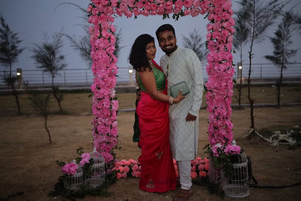 Couple posing for a photo in front of an artificial flower gate