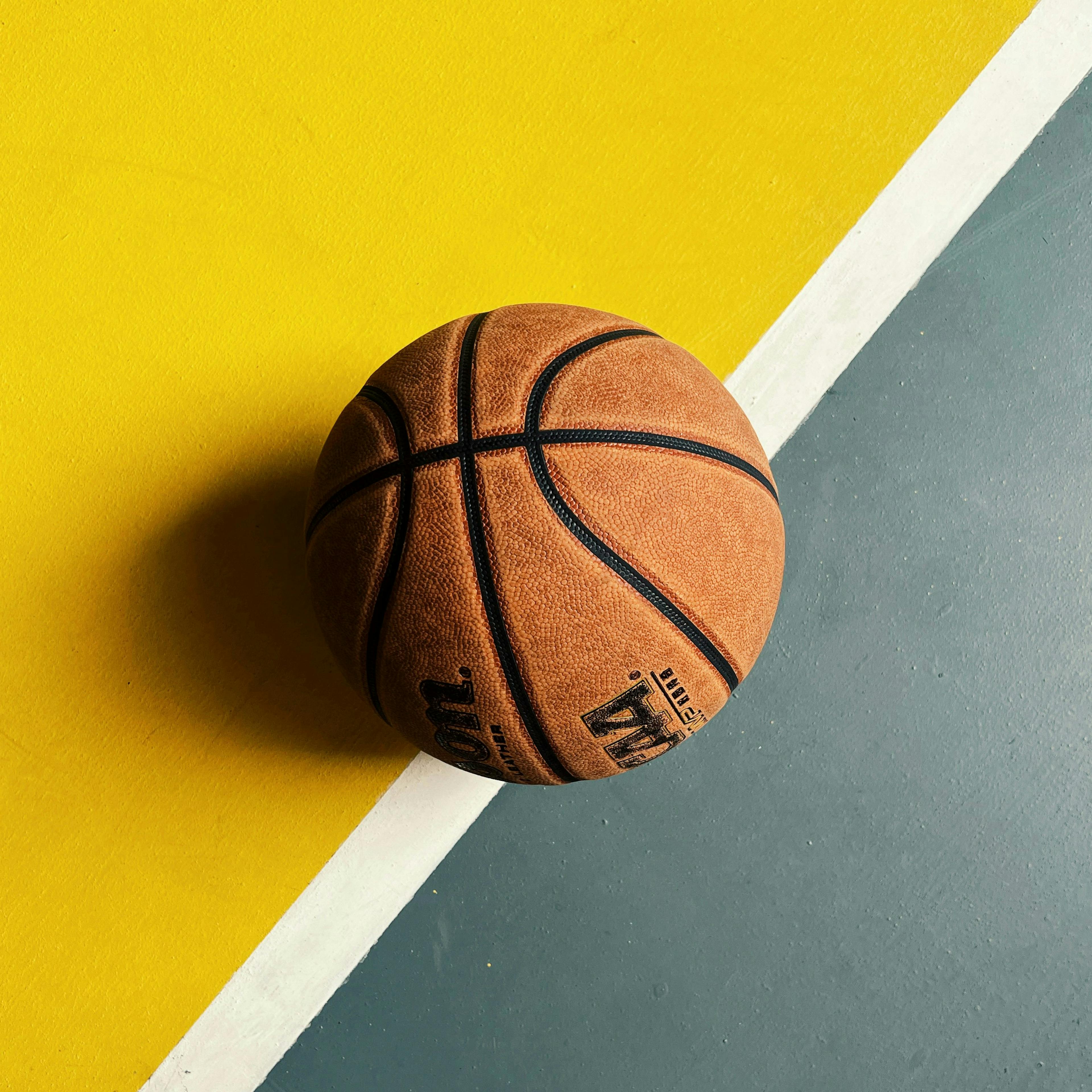 A basketball resting on a rubberized gym floor