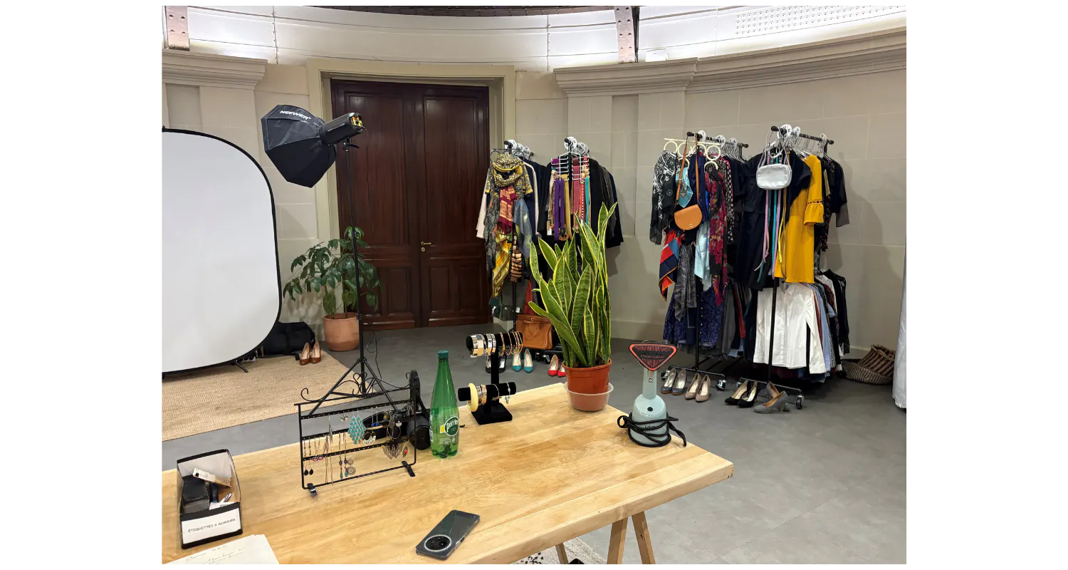 une table en bois en premier plan décoré de plante, porte bijoux, au fond un set up photo et à droite de la photo il y a un dressing