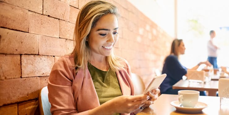 Instagram Direct: mulher sorri enquanto usa celular