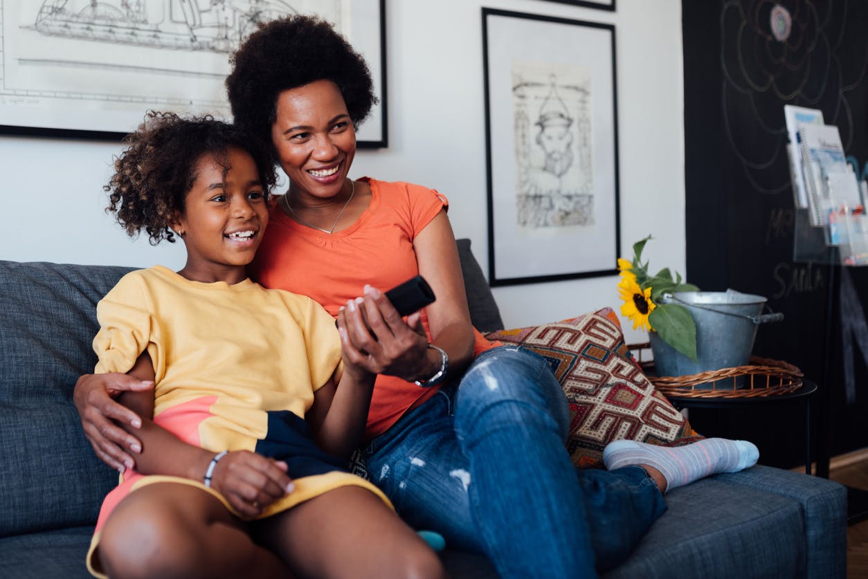 mulher assistindo tv com uma criança sentado em um sofá