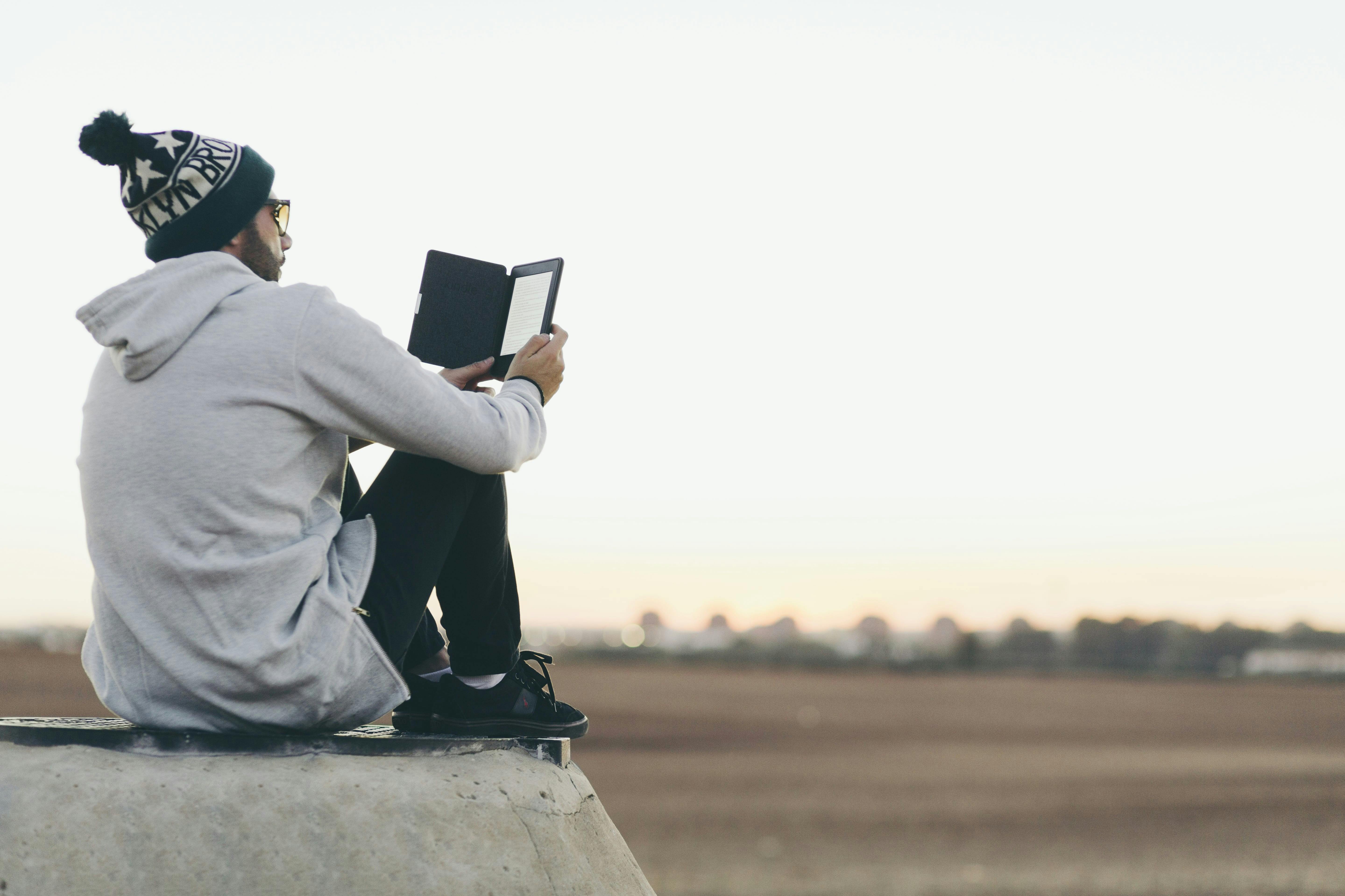homem sentado em um campo aberto olhado o tablet