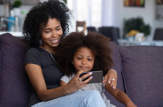 Celular com TV: mãe e filha assistem a programação