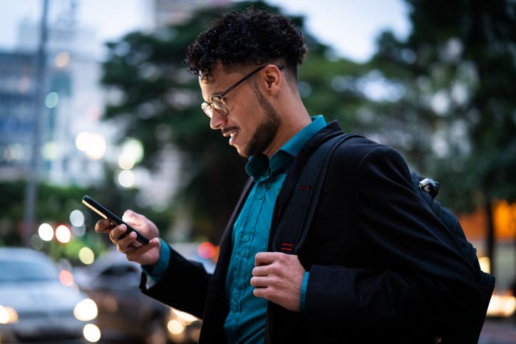 Homem andando na rua e mexendo no celular