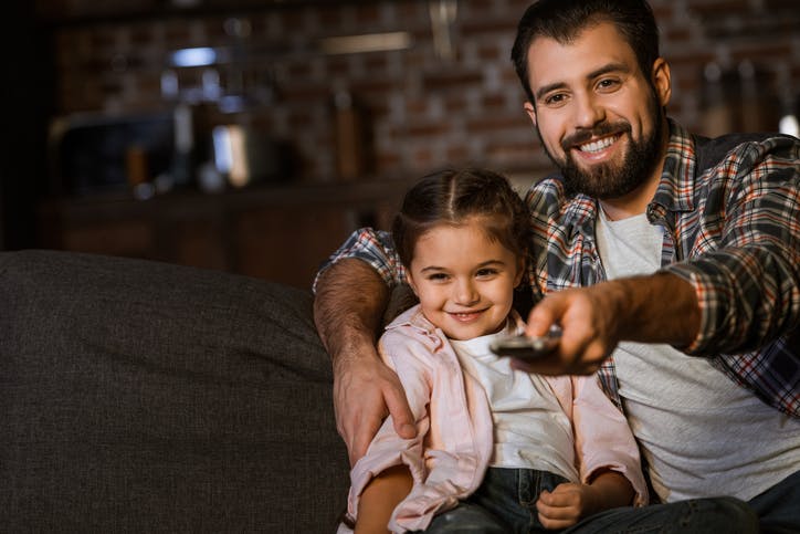 Pai e filha assistindo TV com o Plano Vivo Fixo + TV e Internet