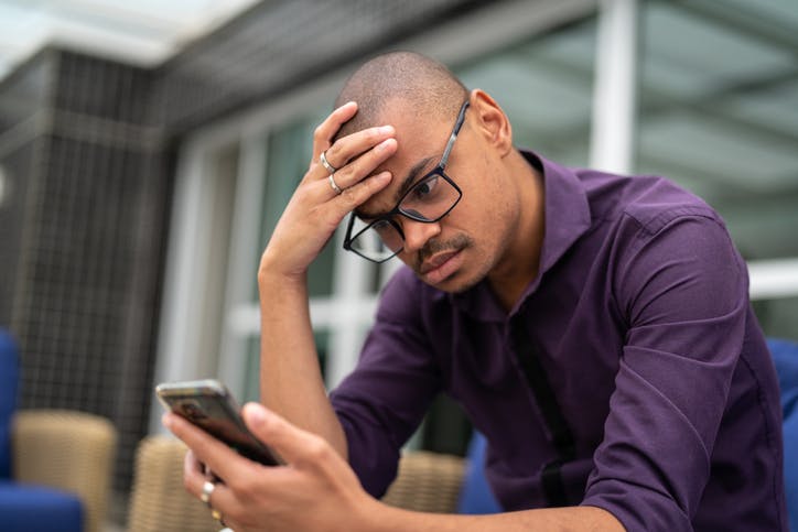 WhatsApp: Homem com expressao preocupada olhando o celular