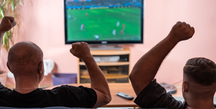 homens comemoram enquanto assistem futebol na tv
