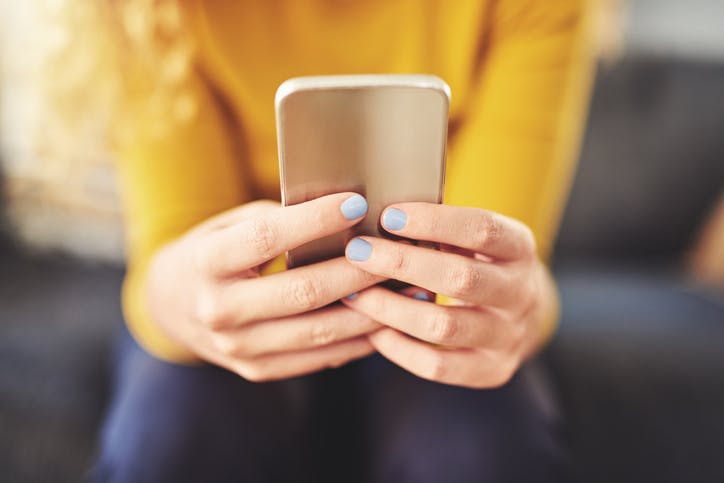 Mulher sentada segurando o celular na mão