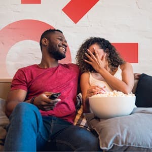 homem e mulher assistindo tv sentados em um sofá