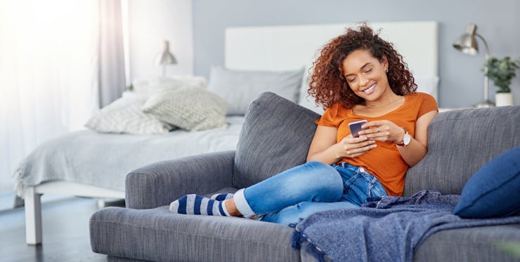 mulher sentada no sofá usando o celular