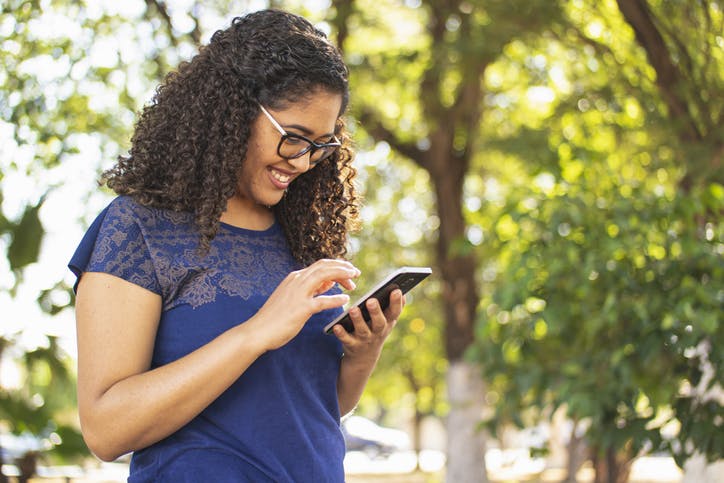 Menina na praça mexendo no celular