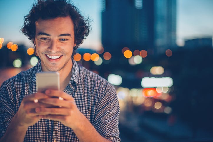 Homem sorrindo digitando o celular