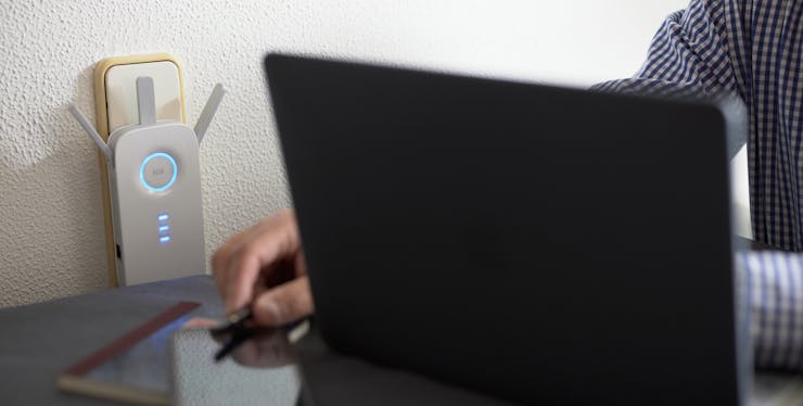 pessoa em um mesa de escritório com um computador e modem wi-fi
