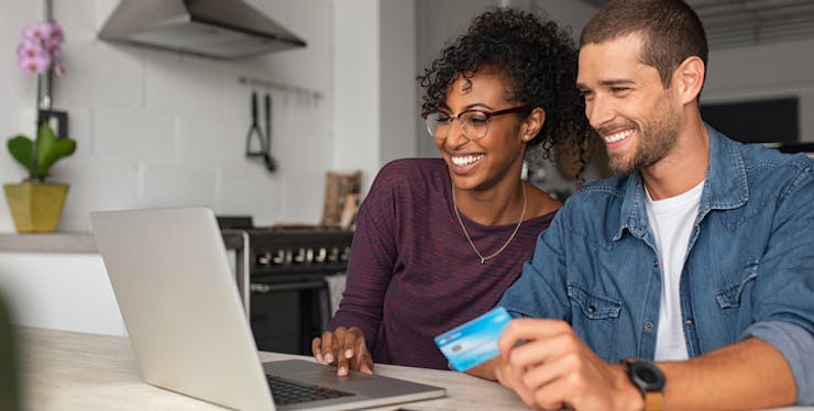Compra segura pela internet: casal usando cartão de crédito e olhando notebook