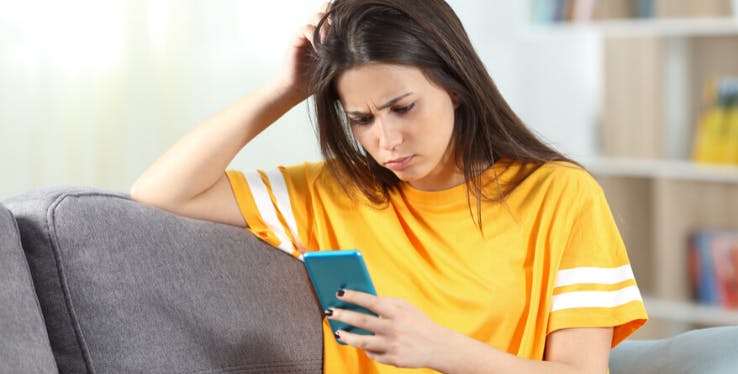 mulher pensativa olhando para o celular